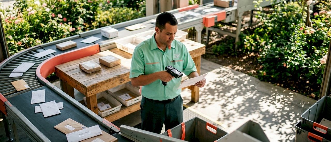 postal worker inspecting machine-readable envelope